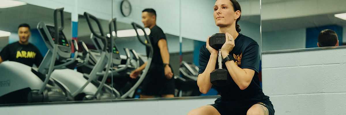 service member lifting weights at the gym on base